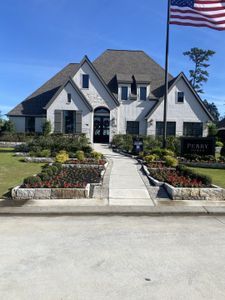 A grand white brick home with a manicured landscape in Evergreen by Perry Homes, offering elegance and timeless curb appeal (Conroe, TX).