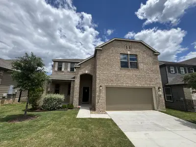 A beautiful brick home with a manicured lawn in McKinney Crossing by KB Home (Austin, TX).