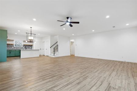 Unfurnished living room with light hardwood / wood-style flooring and ceiling fan with notable chandelier