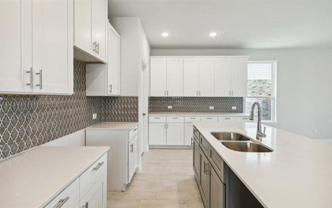 Kitchen featuring decorative backsplash, light countertops, and a sink