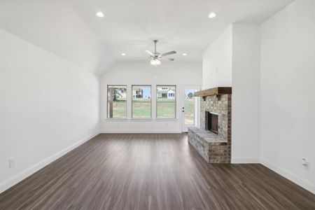 Unfurnished living room with lofted ceiling, a fireplace, dark hardwood / wood-style floors, and ceiling fan