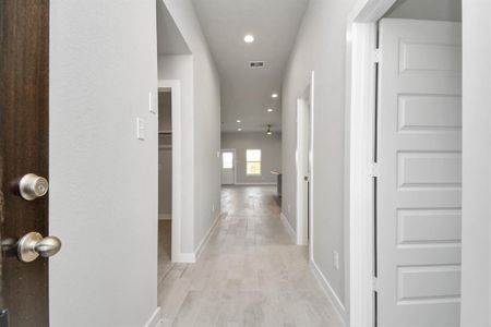 The grand entrance beckons with its soaring ceilings, adorned with elegant wood-look tile flooring featuring sleek oversized baseboards. Sample photo of completed home with similar floor plan. Actual colors and selections may vary.