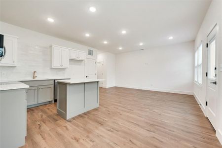 Kitchen with sink, gray cabinetry, tasteful backsplash, light hardwood / wood-style flooring, and a kitchen island