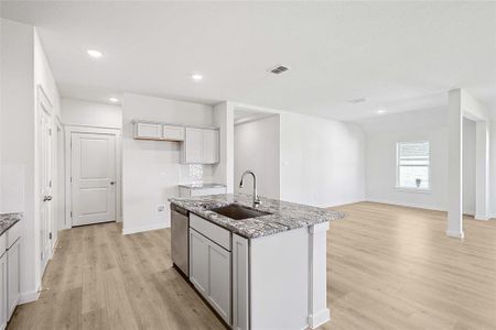 Kitchen with sink, light hardwood / wood-style flooring, a kitchen island with sink, and dishwasher