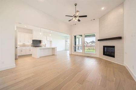 Unfurnished living room featuring a fireplace, ceiling fan, light hardwood / wood-style flooring, and sink