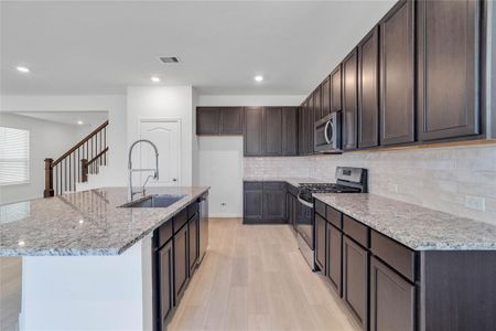 This spacious kitchen features high ceilings, stained wood cabinets, granite countertops, SS appliances, modern tile backsplash, recessed lighting, large kitchen island with space for a breakfast bar, and a pantry all overlooking your huge family room.