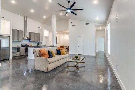 Living room featuring high vaulted ceiling, sink, and ceiling fan with notable chandelier