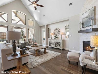 Living room with ceiling fan, a fireplace, high vaulted ceiling, and dark hardwood / wood-style flooring