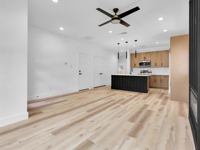 Kitchen with stainless steel appliances, light hardwood / wood-style floors, a kitchen island, and pendant lighting