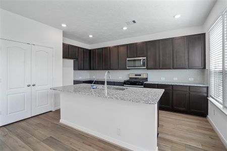 This kitchen is by far any chef’s dream! This spacious kitchen features high ceilings, dark stained wood cabinets, granite countertops, SS appliances, modern tile backsplash, recessed lighting, extended counter space, granite kitchen island with double sink, space for breakfast bar, and a walk-in pantry all overlooking your huge family room.