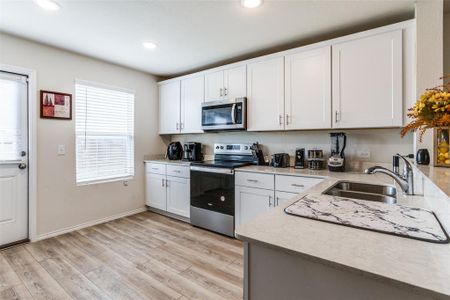 Kitchen featuring white cabinetry, electric stove, sink, light stone counters, and light hardwood / wood-style flooring