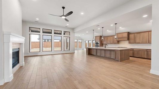 Kitchen featuring decorative light fixtures, light wood-type flooring, an island with sink, ceiling fan, and decorative backsplash