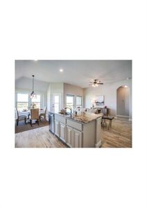 Kitchen featuring stainless steel dishwasher, light stone counters, a center island with sink, light hardwood / wood-style floors, and hanging light fixtures