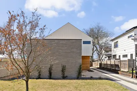 View of side of home with an outbuilding, a lawn, and fence