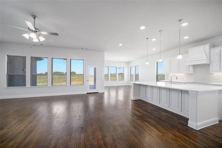 Kitchen with pendant lighting, ceiling fan with notable chandelier, dark hardwood / wood-style floors, a spacious island, and white cabinetry