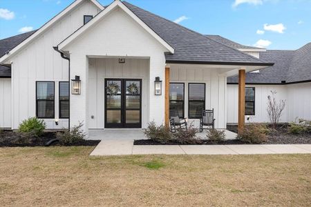 Entrance to property featuring covered porch, french doors, and a lawn