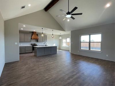 Kitchen featuring hanging light fixtures, dark hardwood / wood-style floors, extractor fan, a center island with sink, and range