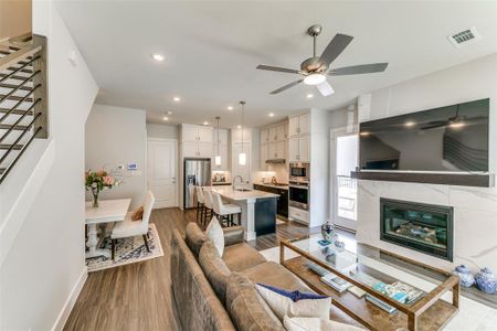 Living room featuring a tile fireplace, hardwood / wood-style flooring, ceiling fan, and sink