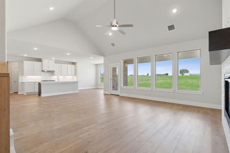 Unfurnished living room with a healthy amount of sunlight, high vaulted ceiling, and light hardwood / wood-style floors