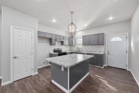 Kitchen with electric range oven, a kitchen island, decorative light fixtures, and gray cabinetry