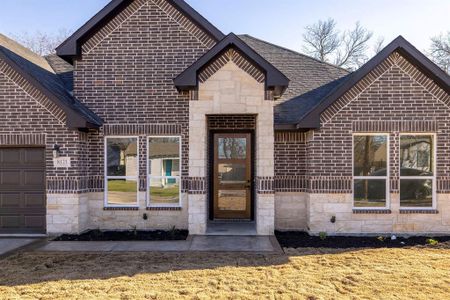 View of front of property featuring stone siding, roof with shingles, and brick siding