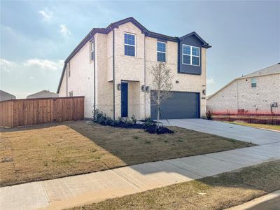 View of front of home with brick siding, an attached garage, fence, a front yard, and driveway