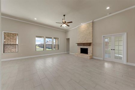 Unfurnished living room with ceiling fan, french doors, crown molding, light hardwood / wood-style floors, and a fireplace