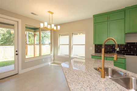 Kitchen with green cabinets, hanging light fixtures, and a wealth of natural light