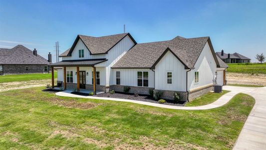 Modern farmhouse style home with a front lawn, covered porch