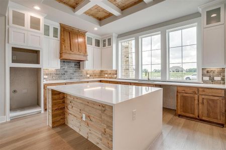 Kitchen featuring backsplash, custom range hood, light hardwood / wood-style floors, and a kitchen island