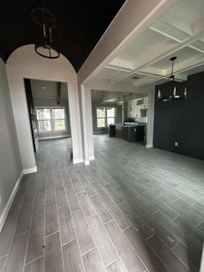 Unfurnished living room with beamed ceiling, baseboards, visible vents, and wood tiled floor