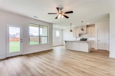 Kitchen featuring ceiling fan, a kitchen island with sink, decorative light fixtures, stainless steel range oven, and light hardwood / wood-style floors