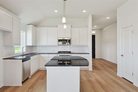 Kitchen with light hardwood / wood-style floors, a center island, stainless steel appliances, sink, and white cabinetry