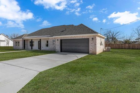 Ranch-style home with a garage, a front lawn, and central air condition unit