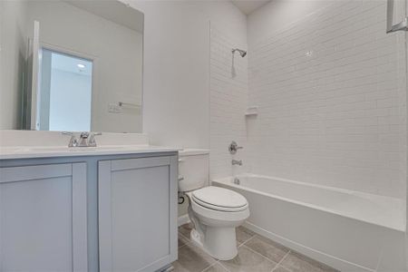 Full bathroom featuring vanity, tiled shower / bath, tile patterned flooring, and toilet