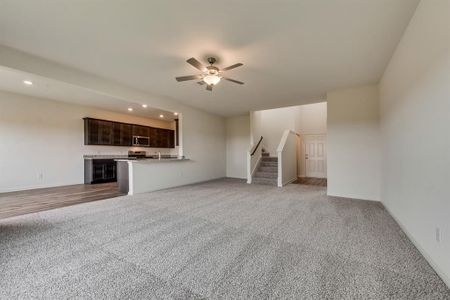 Unfurnished living room featuring light carpet, sink, and ceiling fan