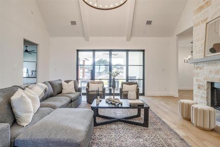 Living room with high vaulted ceiling, a fireplace, hardwood / wood-style flooring, and ceiling fan with notable chandelier