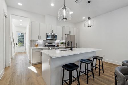 Modern kitchen with sleek white cabinetry, stainless steel appliances, and a spacious island with seating, perfect for entertaining.