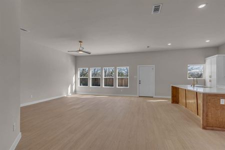 Unfurnished living room featuring sink, a wealth of natural light, and light hardwood / wood-style floors