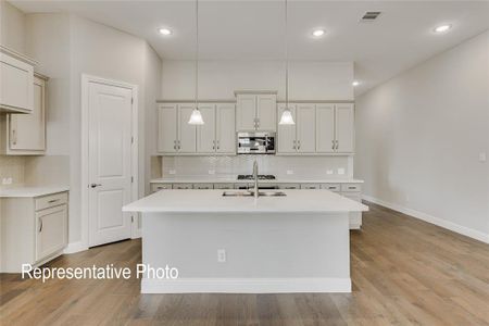 Kitchen with appliances with stainless steel finishes, hanging light fixtures, and light hardwood / wood-style floors