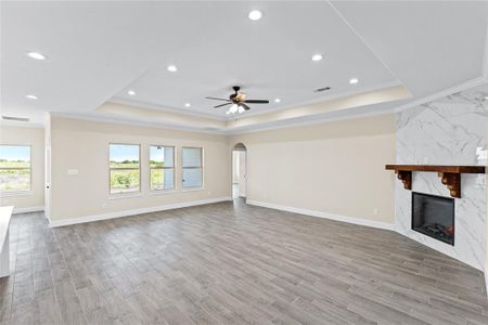 Unfurnished living room with a wealth of natural light, a premium fireplace, and a tray ceiling