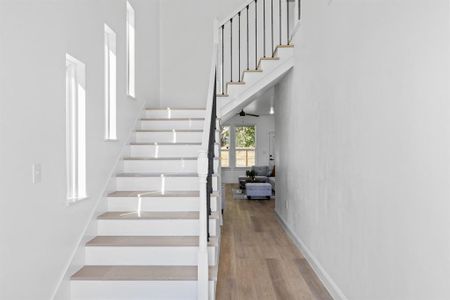 Staircase with hardwood / wood-style flooring and ceiling fan