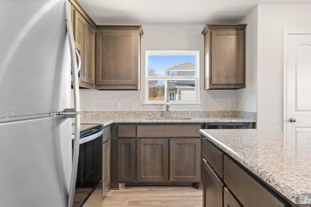 Kitchen featuring sink, light stone counters, fridge, electric range, and light wood-type flooring