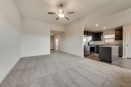 Kitchen with stainless steel appliances, ceiling fan, a center island, dark brown cabinets, and light colored carpet