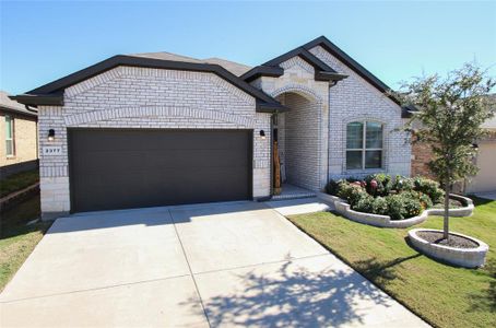 View of front facade featuring a beautiful front yard with new landscaping, stone tree rings, and a garage