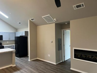 Kitchen featuring black appliances, vaulted ceiling, gray cabinets, electric panel, and dark hardwood / wood-style flooring