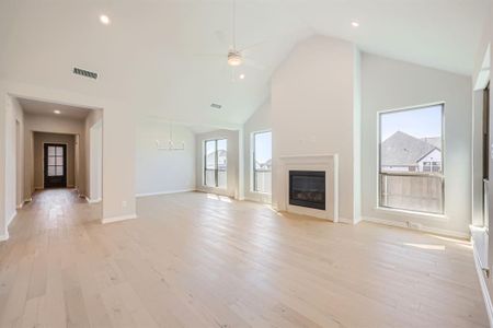 Unfurnished living room with high vaulted ceiling, light wood-type flooring, and a healthy amount of sunlight