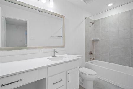 Secondary bathroom features stained cabinets, neutral paint, shower/tub combo with tile surround, large framed mirror, tile floors, and sleek fixtures and modern finishes.