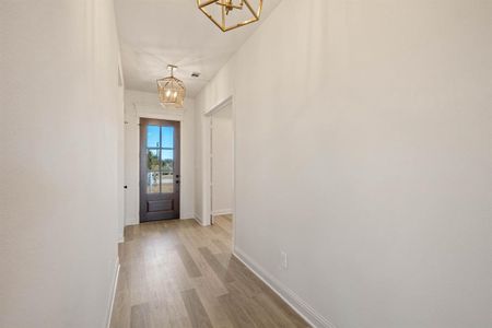 Entryway featuring a chandelier, light wood-type flooring, and baseboards