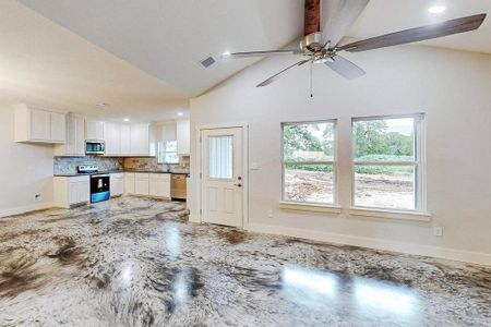 Unfurnished living room with high vaulted ceiling, ceiling fan, and sink